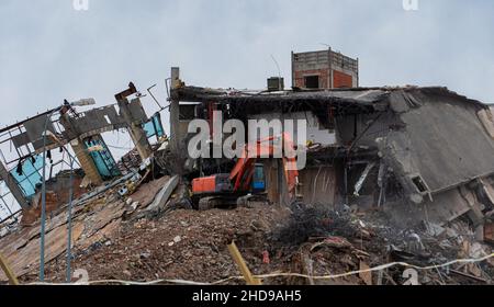 Heavy equipment being used to tear tearing down building construction. Excavator working on a demolition site Stock Photo