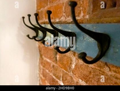 Wrought iron coat hangers place on old blue vintage wood hung on a brick textured wall with a blank leftside for copy space shot in selective focus wi Stock Photo