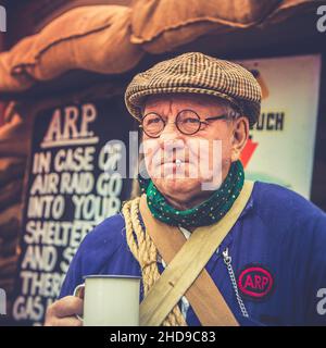 Close up Arthur Lowe lookalike as wartime, 1940 ARP warden (air raid precaution) by shelter, Severn Valley heritage railway 1940s WW2 summer event UK. Stock Photo