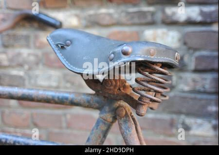 Closuep shot of a very old rusty bicycle saddle against a brick wall