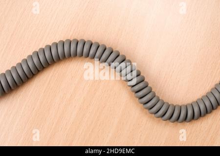 Phone cord on wooden table. Stock Photo