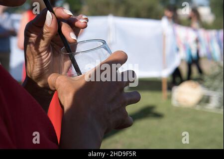 Selective focus shot of a woman drinking from a glass with a plastic stick Stock Photo