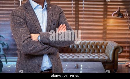 Unrecognizable businessman wearing a suit standing with crossed arms in the office Stock Photo