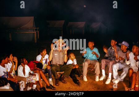federal park ranger telling stories to children around a campfire at Floyd Bennett field in Brooklyn NYC Stock Photo