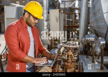 Skillful multiethnic engineer working at heavy industry plant Stock Photo