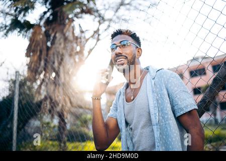 Handsome latin american man using his smartphone smiling on the street Stock Photo