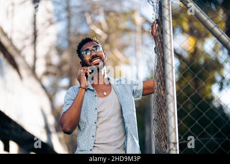 Handsome afro man using his smartphone on the street smiling Stock Photo