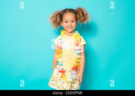 Happy little girl wearing Hawaiian necklace standing isolated over green background. Stock Photo