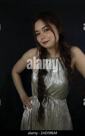 Portrait of an attractive young woman from Vietnam in a shiny dress with dark background Stock Photo