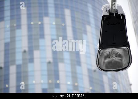 Close up of lamp post with icicles pictured with a modern office building in background. Stock Photo