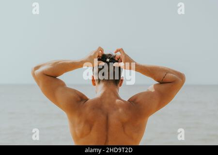 Young Spanish sporty male waring swimming goggles on the beach Stock Photo