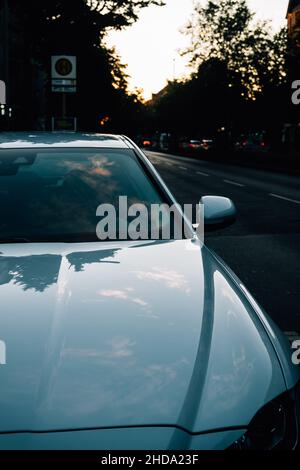 Closeup shot of a parked car in the street with reflections on it Stock Photo