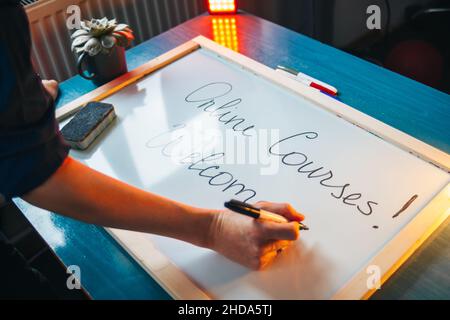 Portrait of woman's hands writing on a white board the greeting to online courses before start the lesson. Online education, courses. Stock Photo