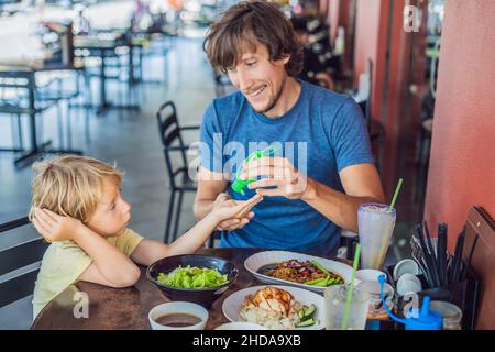 Father and son using wash hand sanitizer gel before eating in a cafe Stock Photo