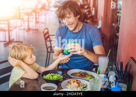 Father and son using wash hand sanitizer gel before eating in a cafe with sunlight Stock Photo