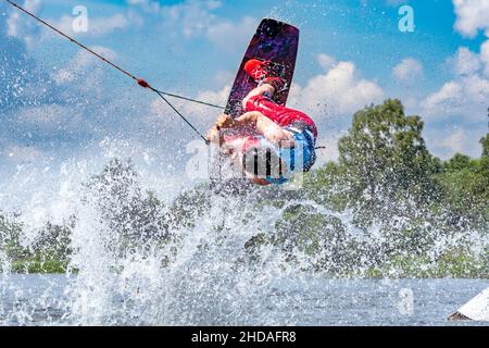 young active professional athlete jumping in the air on a wakeboard, water sports in the river Stock Photo