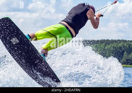 young active professional athlete jumping in the air on a wakeboard, water sports in the river Stock Photo