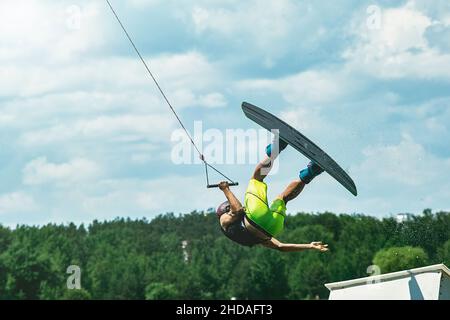 young active professional athlete jumping in the air on a wakeboard, water sports in the river Stock Photo
