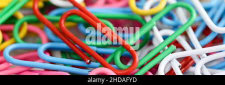 Lots of multi-colored paper clips of same size on table. Stock Photo
