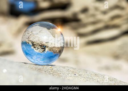 Upside down seascape with blue sky and rocks - reflection in a lens ball - selective focus, space for text Stock Photo