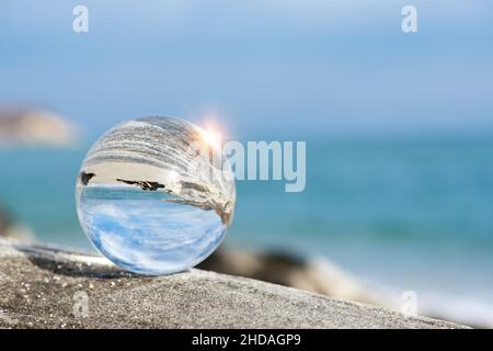 Upside down seascape with blue sky and rocks - reflection in a lens ball - selective focus, space for text Stock Photo