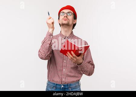 Waist-up portrait of funny male scientist working on project, passionatly look up and raise pen as have perfect idea, holding notebook, writing down Stock Photo
