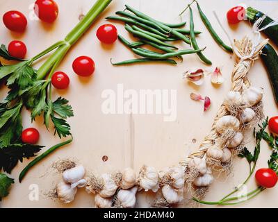 Top view of a garlic braid, Cherry tomatoes, beans, zucchini and celery on wooden table Stock Photo