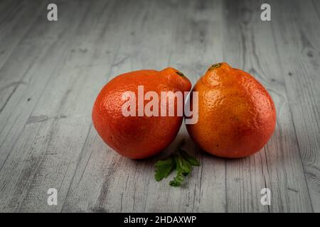 A closeup shot of two oranges on a wooden table Stock Photo