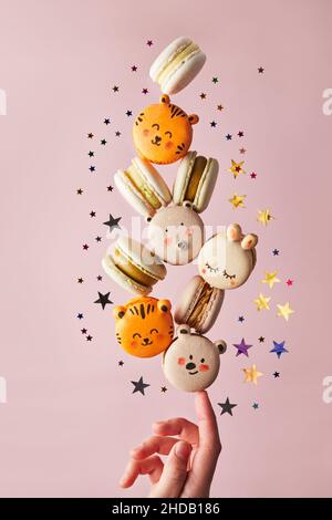 Photo of macaron in the form of beasts balancing on the finger of the hand. Levitation photo. Front view. Stock Photo