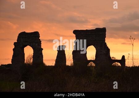 Photos taken at sunset while on a stroll through the beautiful Aqueducts Park in Rome, with the majestic ruins of ancient Roman aqueducts and trees Stock Photo