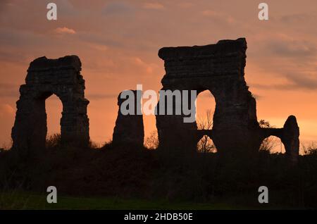 Photos taken at sunset while on a stroll through the beautiful Aqueducts Park in Rome, with the majestic ruins of ancient Roman aqueducts and trees Stock Photo