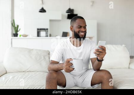 Black man using his smartphone drinking coffee Stock Photo