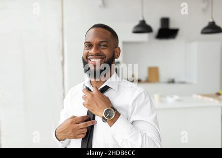 Smiling Confident African American Businessman Adjusting Tie Looking Away Stock Photo