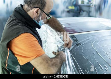 Repairing car body, Application putty close up. The mechanic repair the  car. Work after the accident by working sanding primer before painting.  Stock Photo