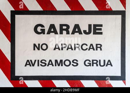 Garage warning sign, no parking, tow truck warning, painted on the wall at the entrance of a garage in Spanish. Stock Photo
