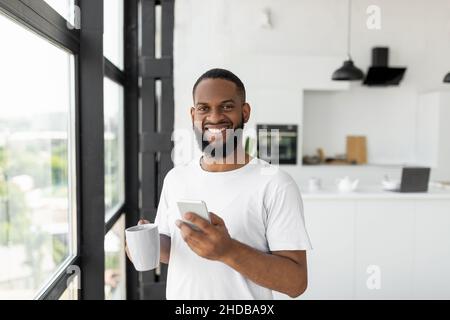 Black man using his smartphone drinking coffee Stock Photo