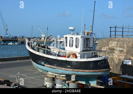 A small fishing boat undergoing repairs at the side of the harbour in St Peter Port, Guernsey, a British crown dependency in the Channel Islands. Stock Photo