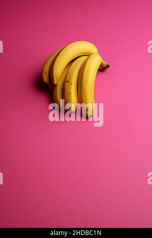 Vertical closeup of a bunch of bananas on pink background. Stock Photo