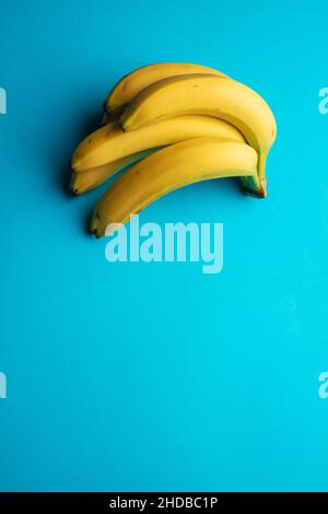 Vertical closeup of a bunch of bananas on blue background. Stock Photo