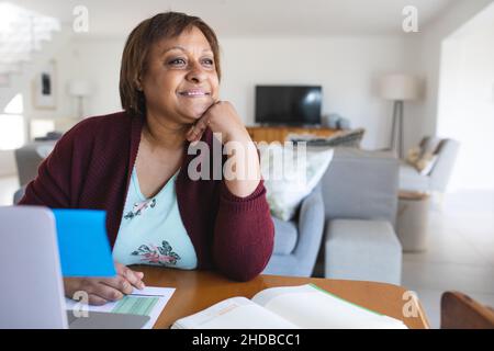 Thoughtful senior woman with laptop during online doctor consultation at home Stock Photo
