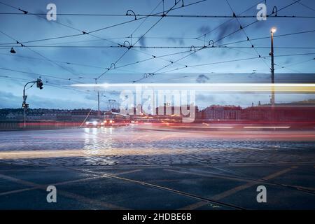 Light trails of tram in Prague downtown. Busy road intersection in city at rainy evening. Stock Photo