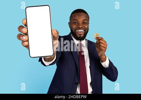 Black Businessman Holding Golden Bitcoin Coin And Showing Blank Mobile Phone Stock Photo