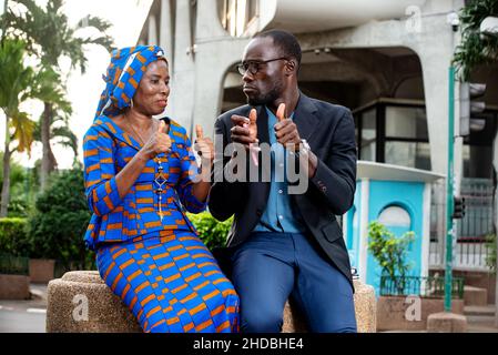 beautiful african couple sitting outdoors making okay sign. Stock Photo