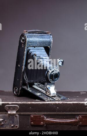 Old vintage camera lying on suitcase on gray background Stock Photo