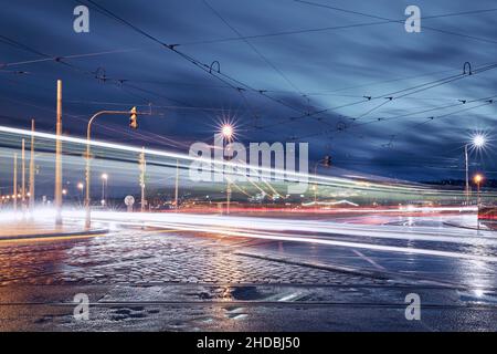 Light trails of trams and cars in Prague downtown. Busy road intersection in city at rainy evening. Stock Photo