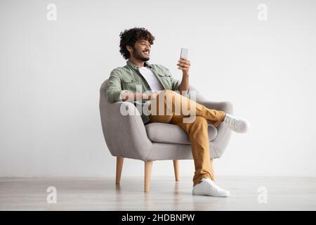 Cheerful young indian man chatting with girlfriend, using smartphone Stock Photo