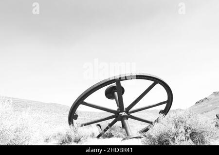 Black and white high key rendition of wheel at Bodie State Park, on a cloudless day and plenty of copy-space. Bodie is a California gold mining ghost Stock Photo