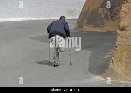 Disabled one-legged man on crutches walks in the street, Andalusia, Spain, Europe Stock Photo