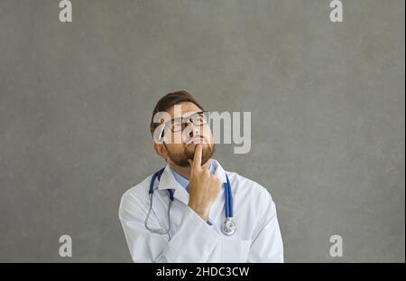 Portrait of man doctor wearing uniform thinking with finger on chin looking up Stock Photo