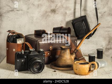 A cup of aromatic coffee. Old film cameras, photographic film, leather case for photographic equipment. Old photographic equipment. Film photography n Stock Photo